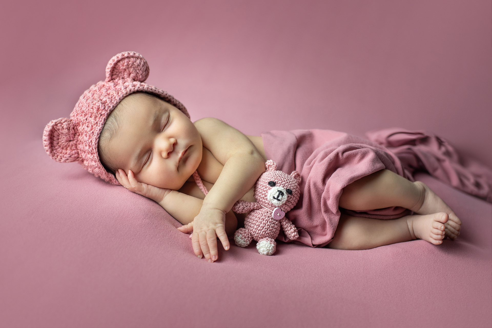 Bebé durmiendo con gorrito rosa en una sesión de fotos para recién nacidos en Velia Studio